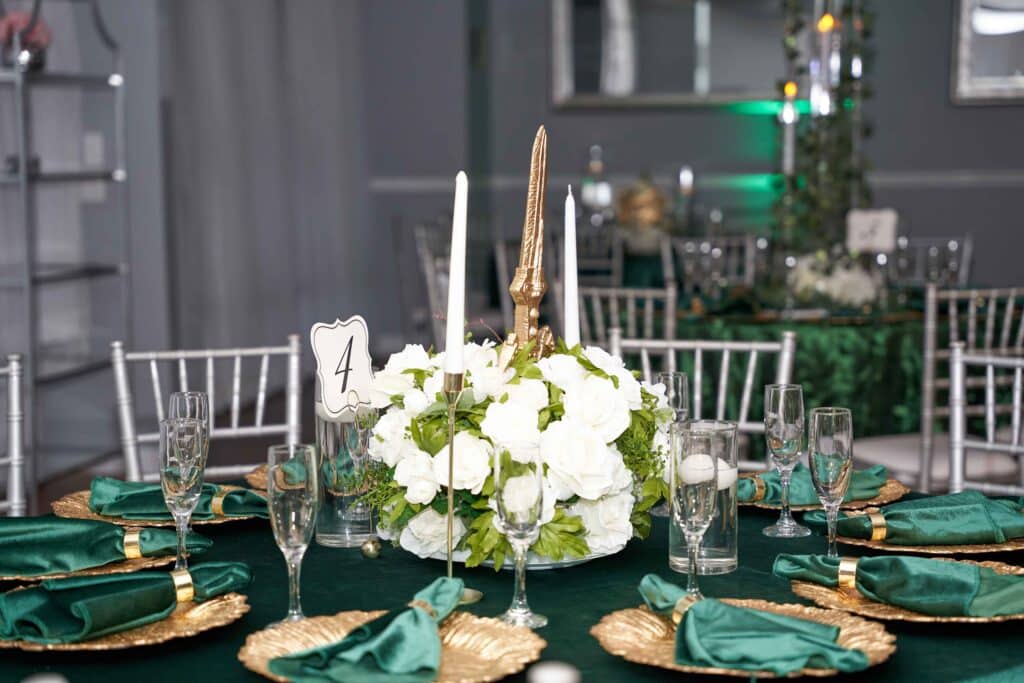 Emerald tablescape with white hydrangea centerpiece and gold chargers, February 2024
