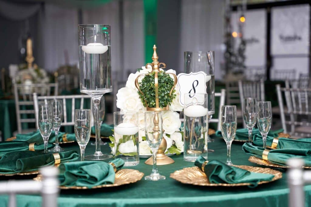 Emerald and gold table setting with a white floral centerpiece, February 2024