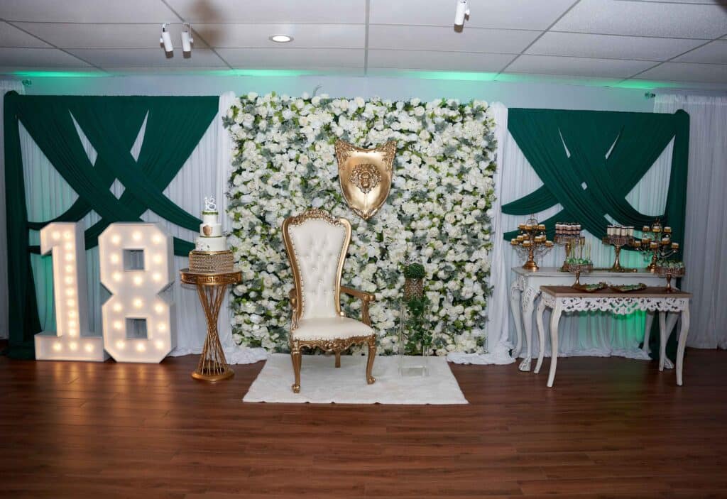 Emerald and gold 18th birthday backdrop with marquee numbers and a gold throne chair, February 2024