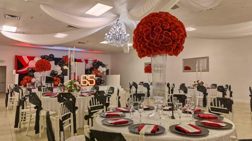 Red, black and white ballroom with rose centerpieces and marquee numbers, October 2024