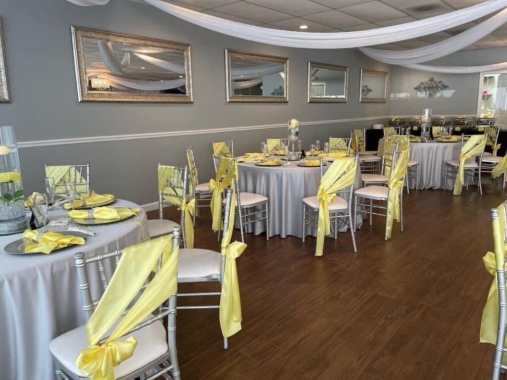 Yellow and white reception with yellow chair sashes and round tables
