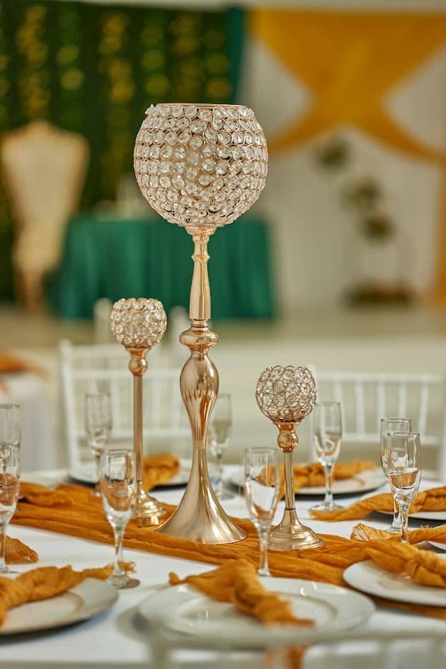 Gold crystal candelabra centerpiece on a set table with amber napkins